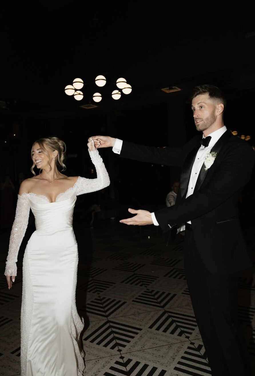 A bride with an updo laughing mid twirl during the first dance