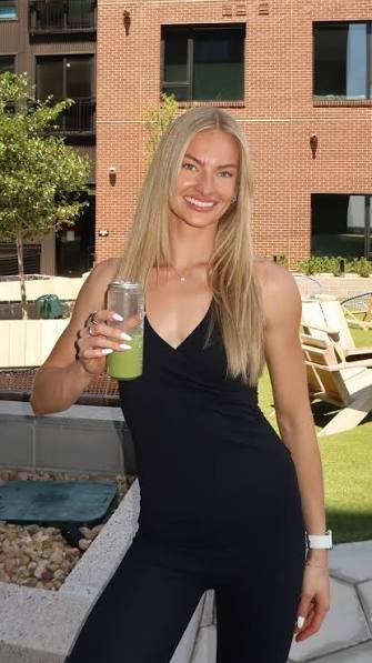Maddie Milton, Pilates and Lagree instructor in Denver, with a green juice on a rooftop patio