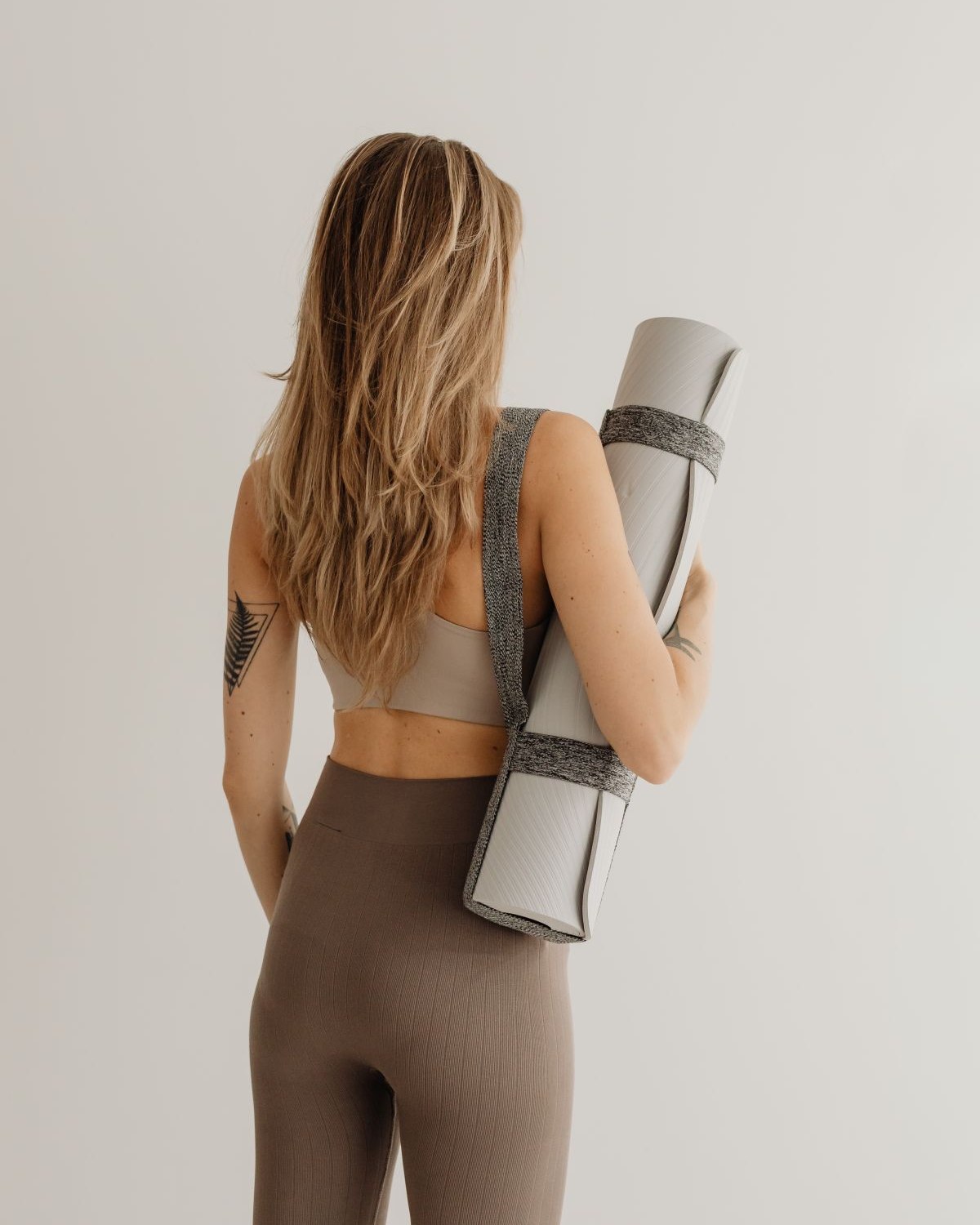 A woman carrying her mat to an appointment, the kind of first visit a wellness website has to make easy