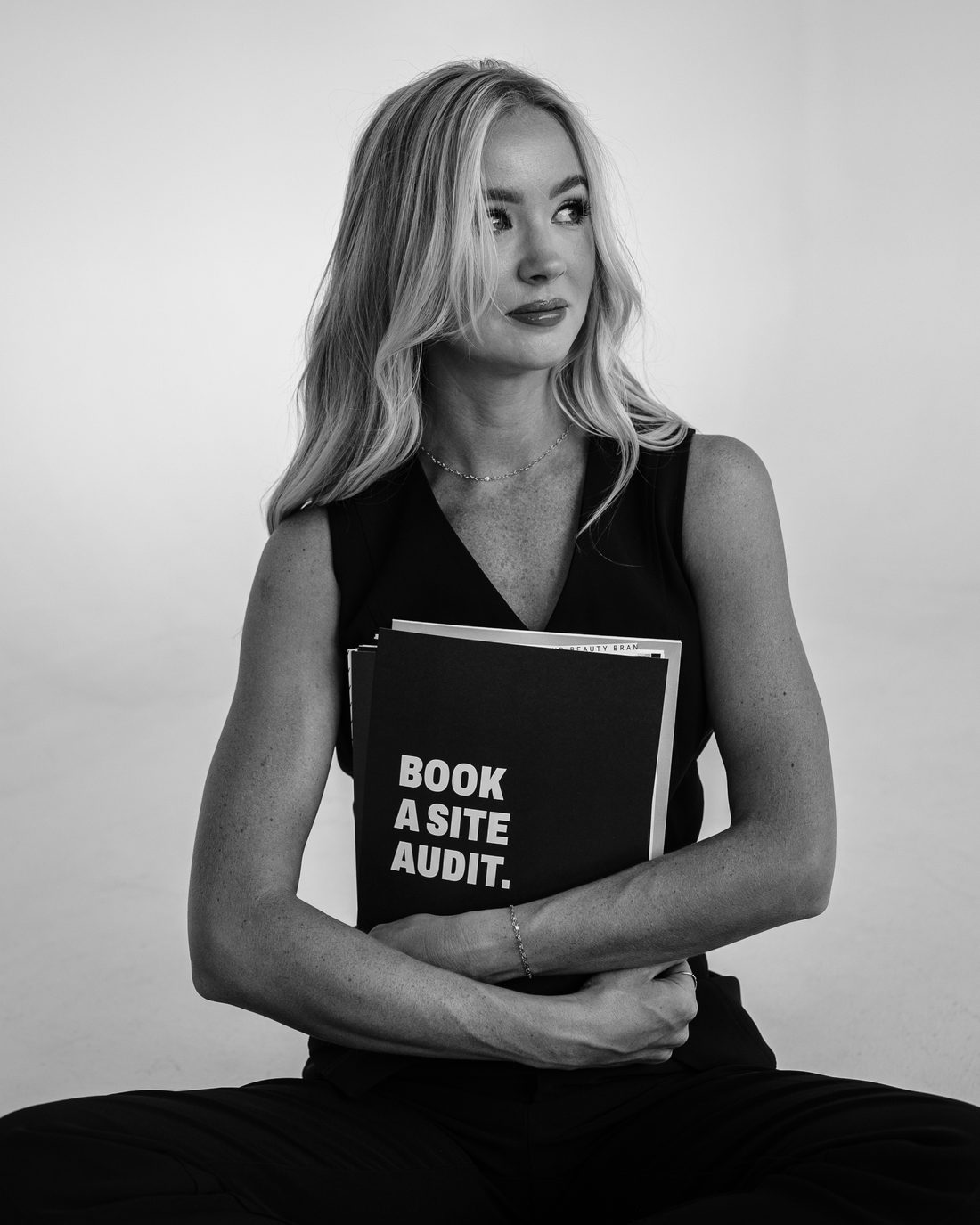 Sabrina, Denver web designer, holding a book titled Book a Site Audit