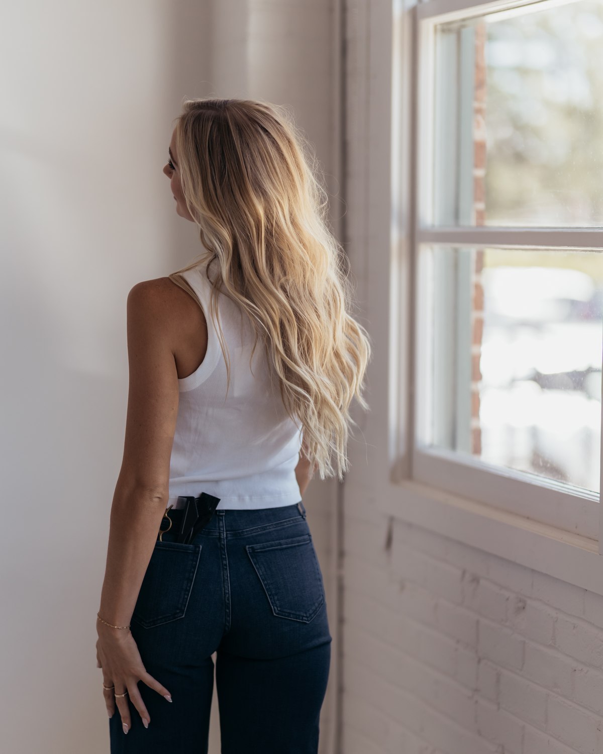 A stylist by the window in a bright salon, color tools in her back pocket, the salon a website has to feel like